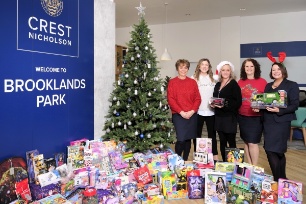 Crest Nicholson staff and Next Link standing next to Christmas tree surrounded by presents